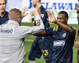 Jim Curtain and Cory Burke high five before a congratulatory hug is given during his goal celebration.