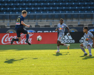 Brandon Craig leaps through the air while Red Bulls II defenders look on.