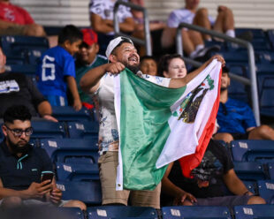 A fan supporting Queretaro F.C., shakes a flag from Mexico celebrating their only goal on the night.