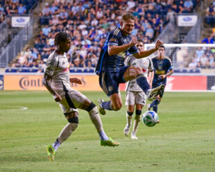 Bruno Damiani explodes through the ball to blocking the clear by Kyle Duncan.